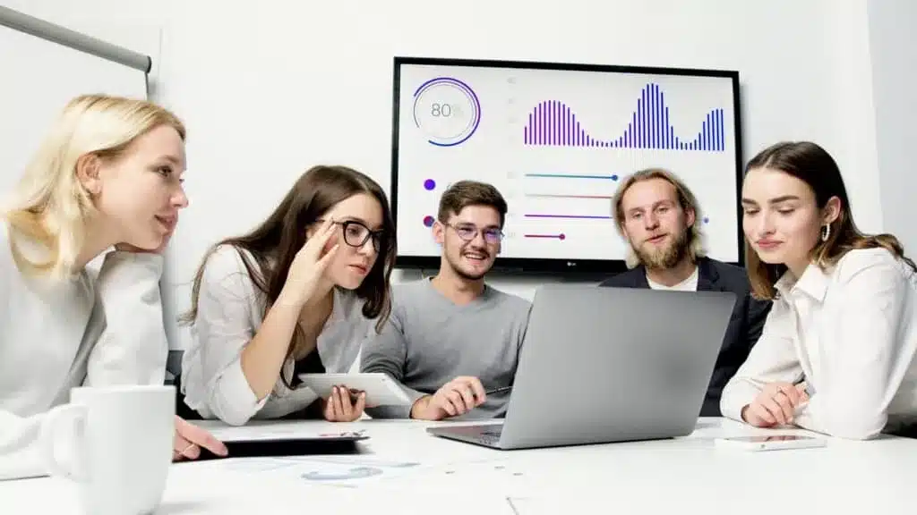 roupe de jeunes professionnels discutant d'analyses graphiques affichées à l'écran lors d'une réunion en entreprise